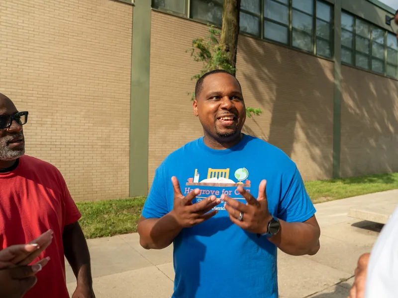 Anthony Hargrove gesturing as he speaks with adults outdoors.