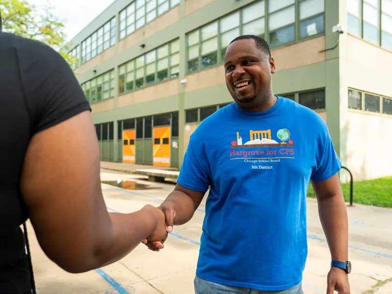 Anthony Hargrove shaking hands with a woman outdoors.