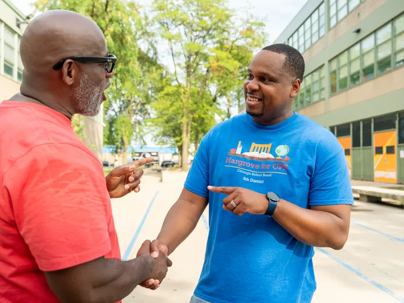 Anthony Hargrove shaking hands with a man in a red shirt.