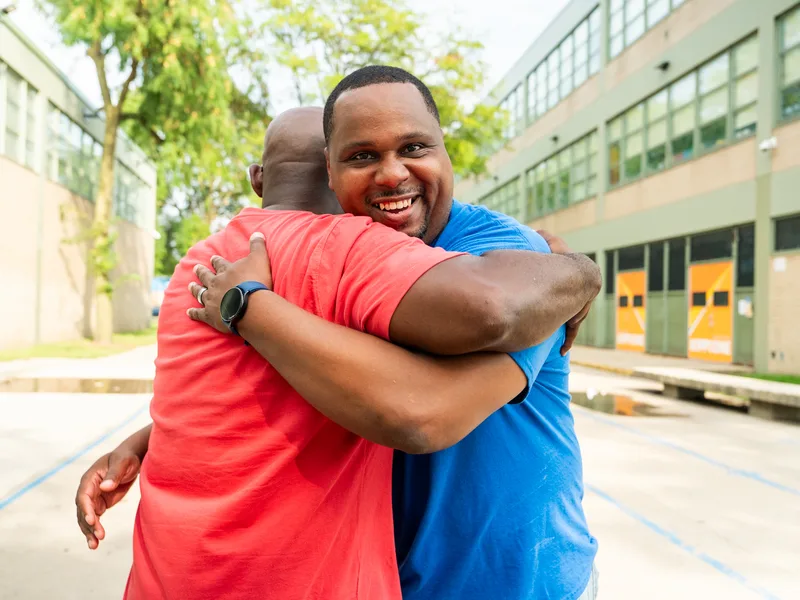 Anthony Hargrove smiling as he embraces a man in a red shirt.