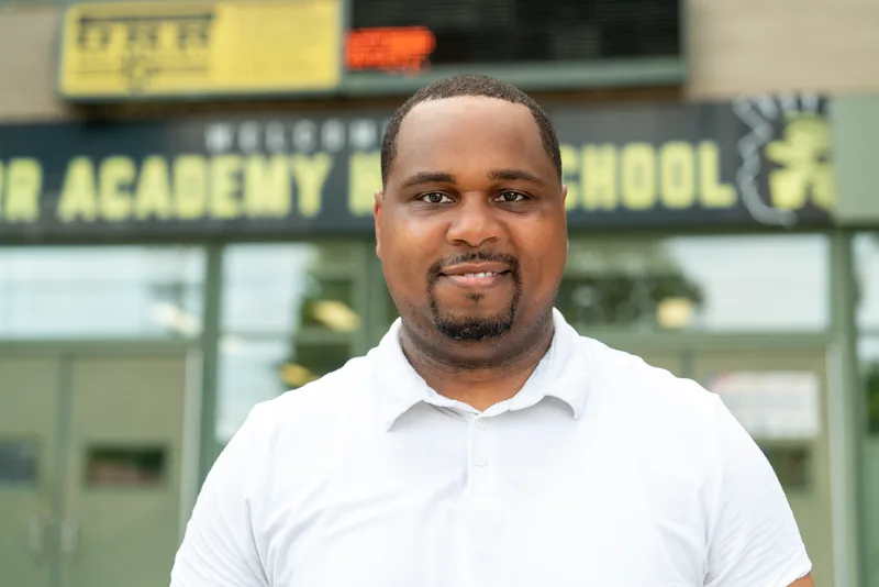 Anthony Hargrove in a white polo shirt with a school sign behind him.