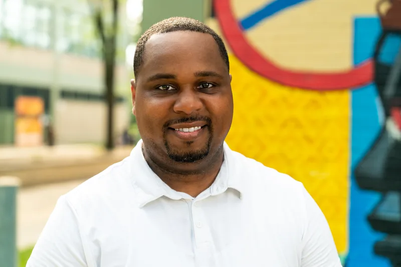 Close portrait of Anthony Hargrove in a white polo shirt beside a colorful mural.