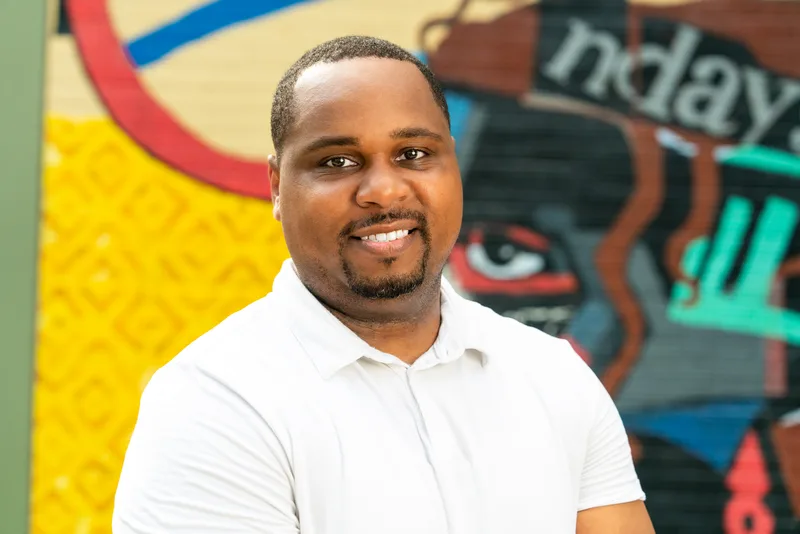 Anthony Hargrove standing at an angle in a white polo shirt beside a mural.
