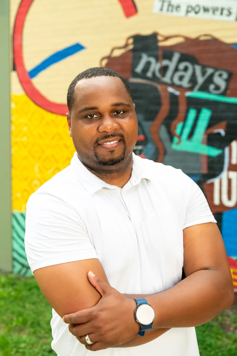 Vertical portrait of Anthony Hargrove with folded arms in front of a mural.