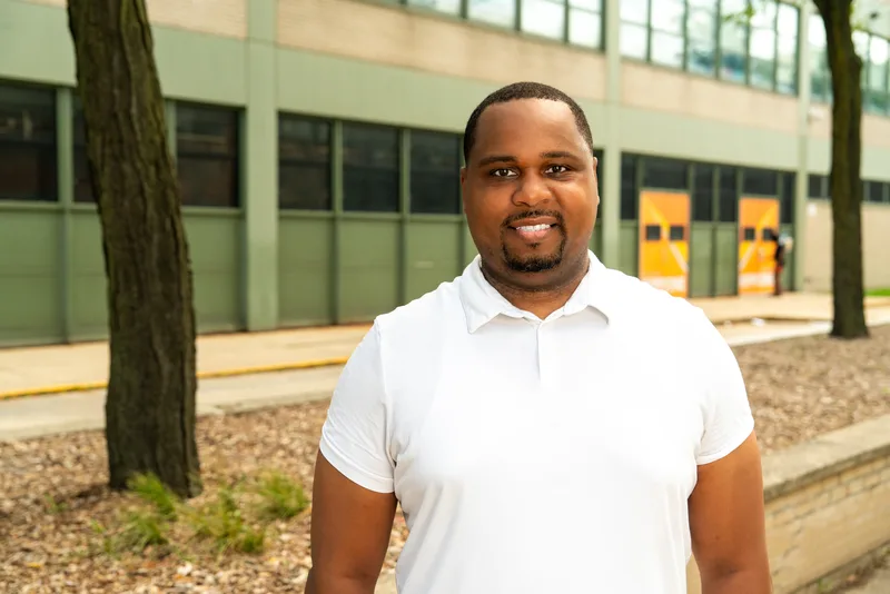 Anthony Hargrove in a white polo shirt with a school and trees behind him.