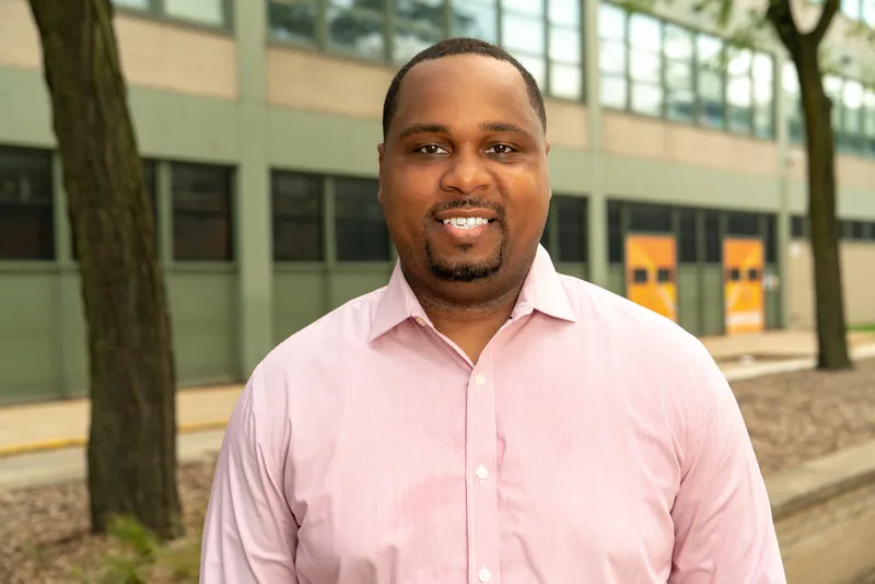 Close portrait of Anthony Hargrove smiling in a pink shirt outdoors.
